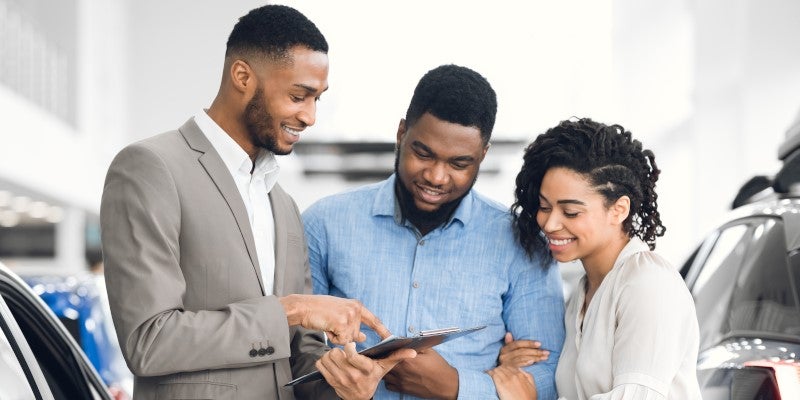 salesman with a couple looking at forms in showroom